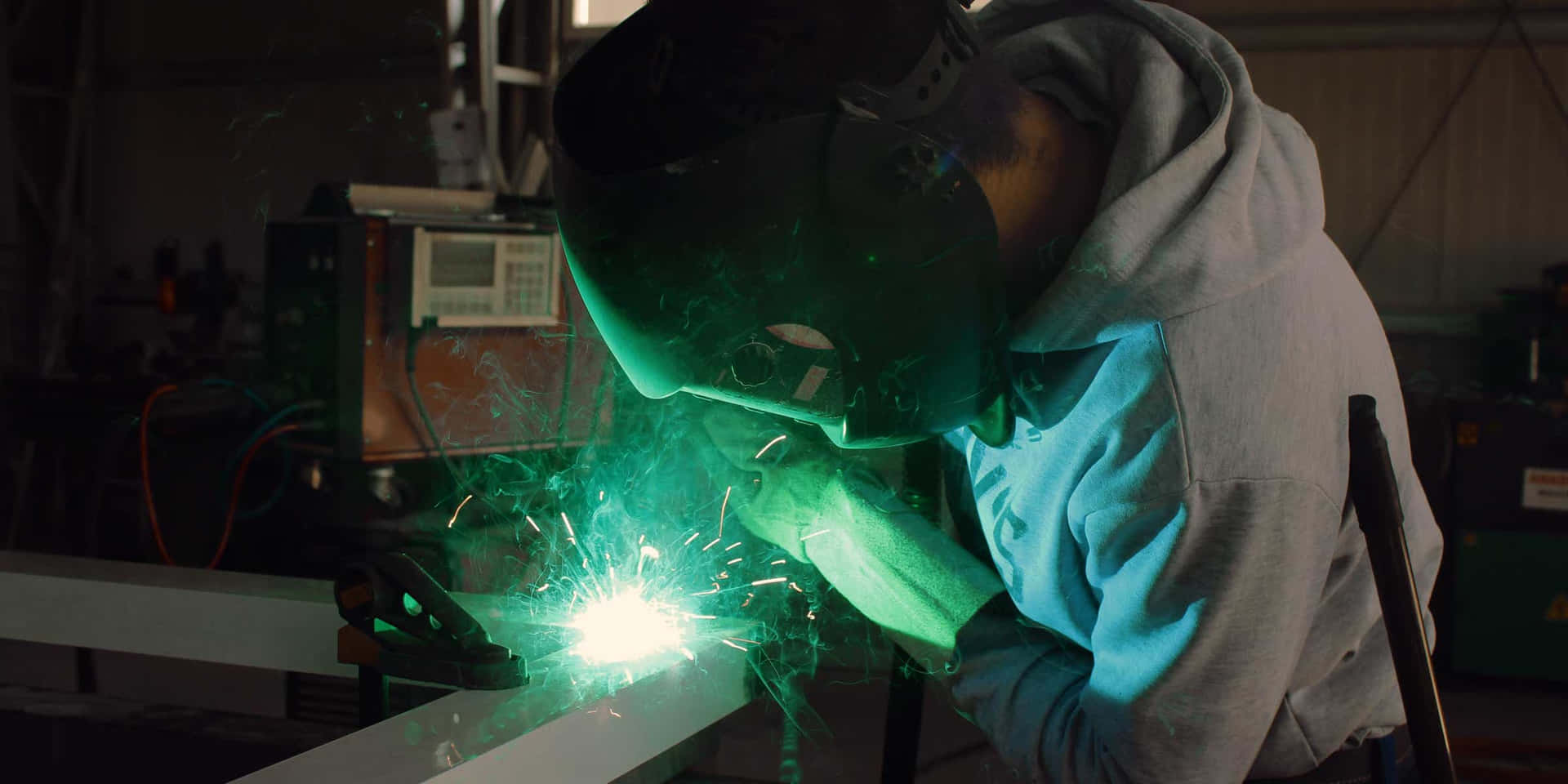A Man Welding Metal In A Factory Background