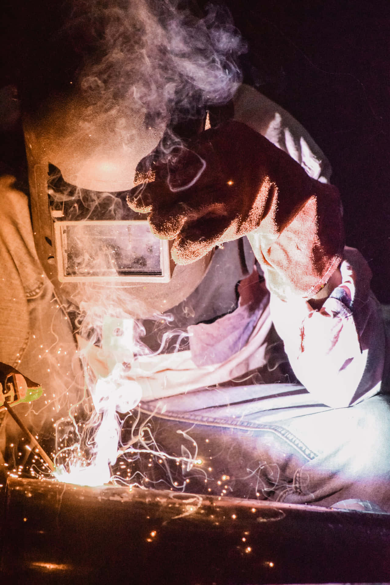 A Man Welding On A Car At Night