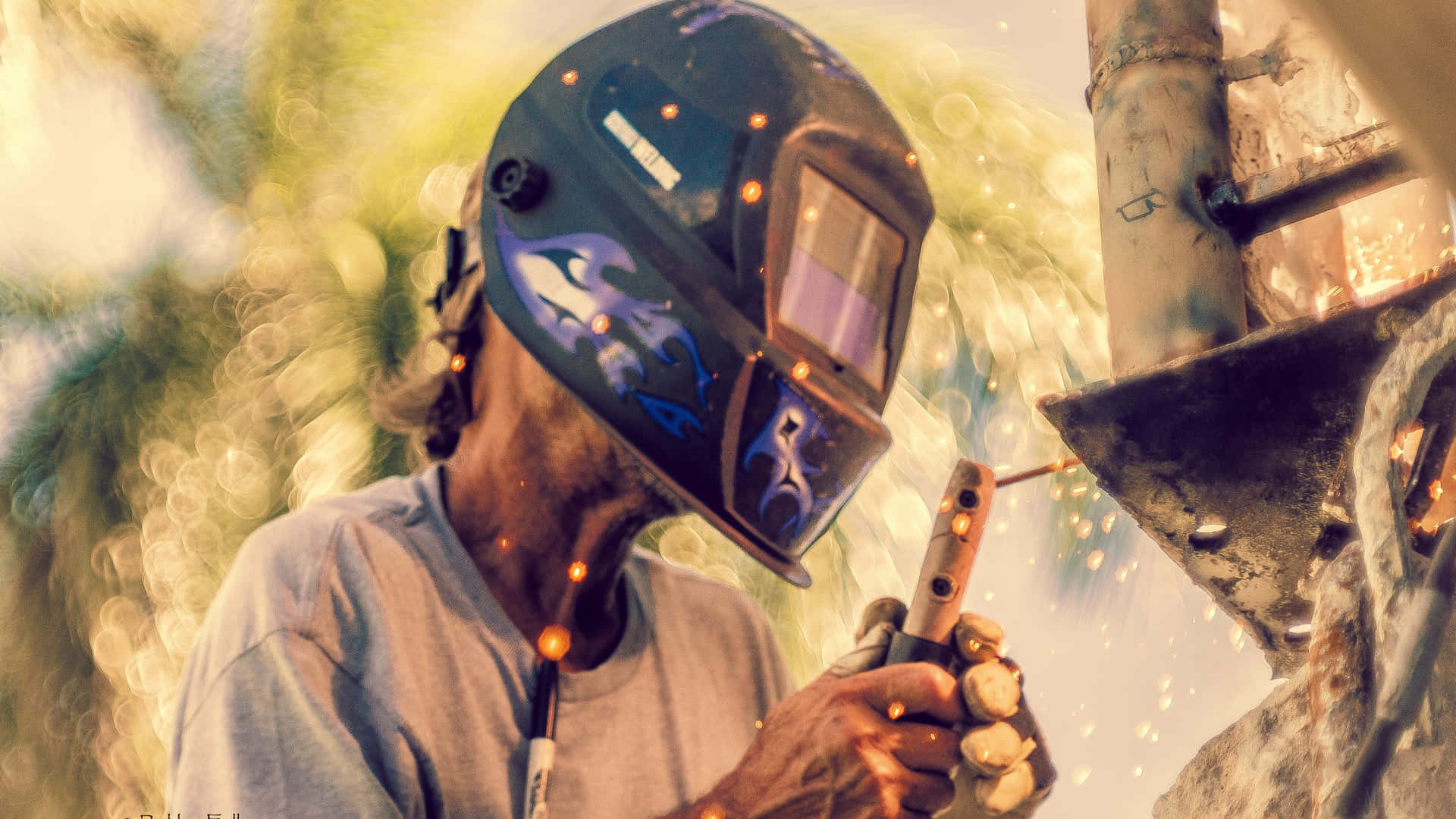A Man Welding With A Helmet On A Piece Of Metal Background