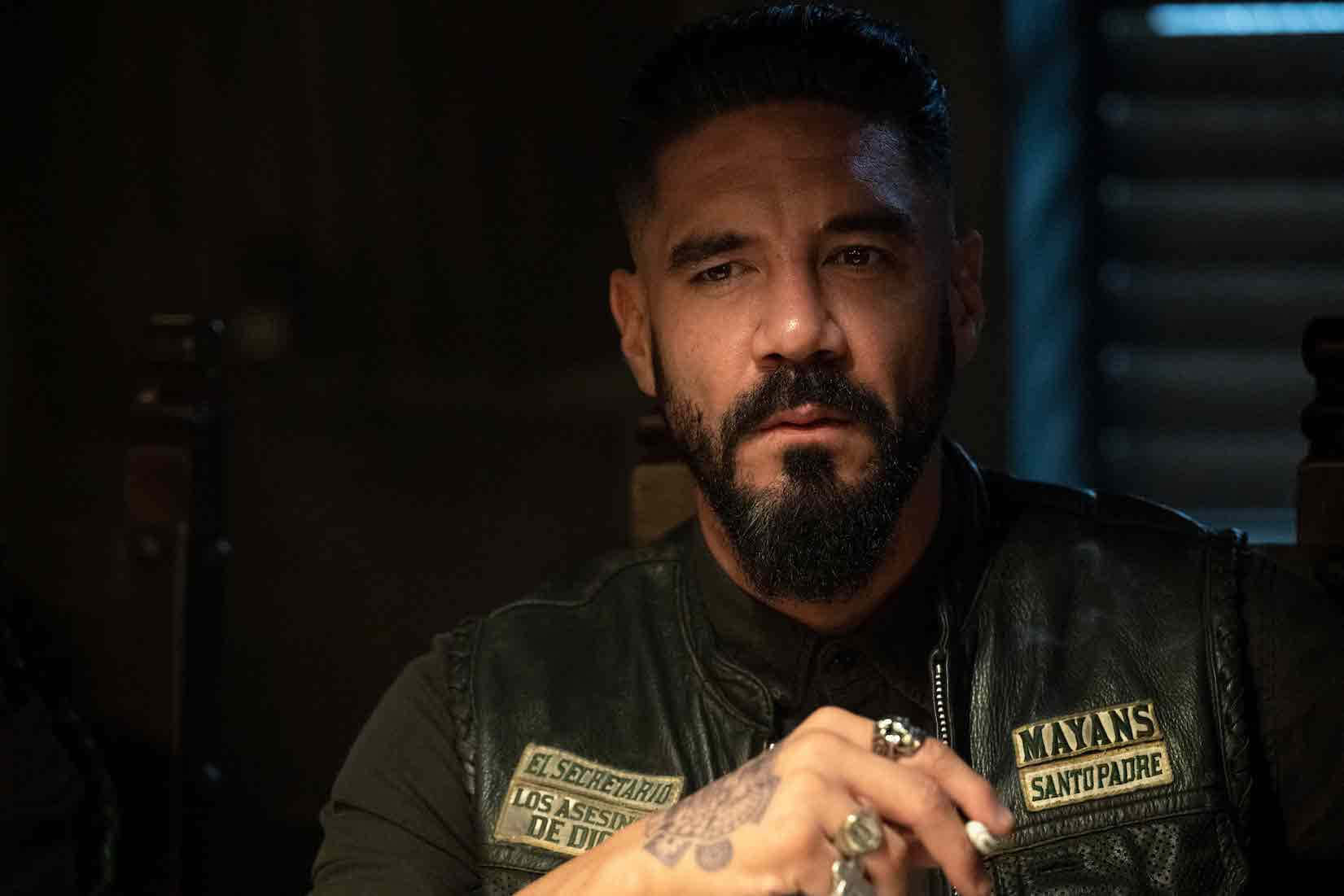 A Man With A Beard And Tattoos Sitting At A Table Background