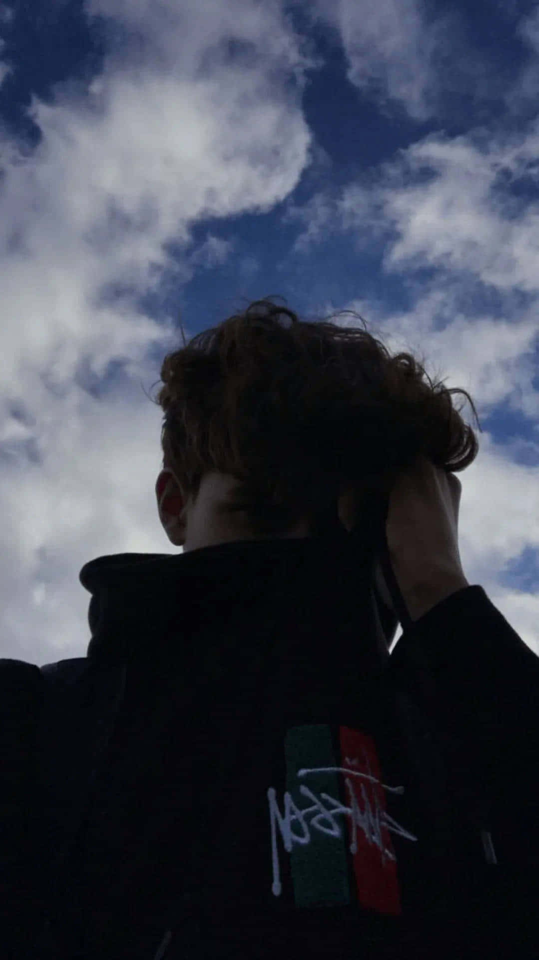 A Man With A Black Hoodie And A Cloudy Sky