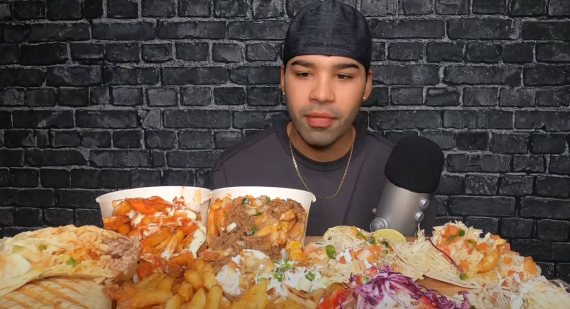 A Man With A Microphone In Front Of A Large Plate Of Food Background