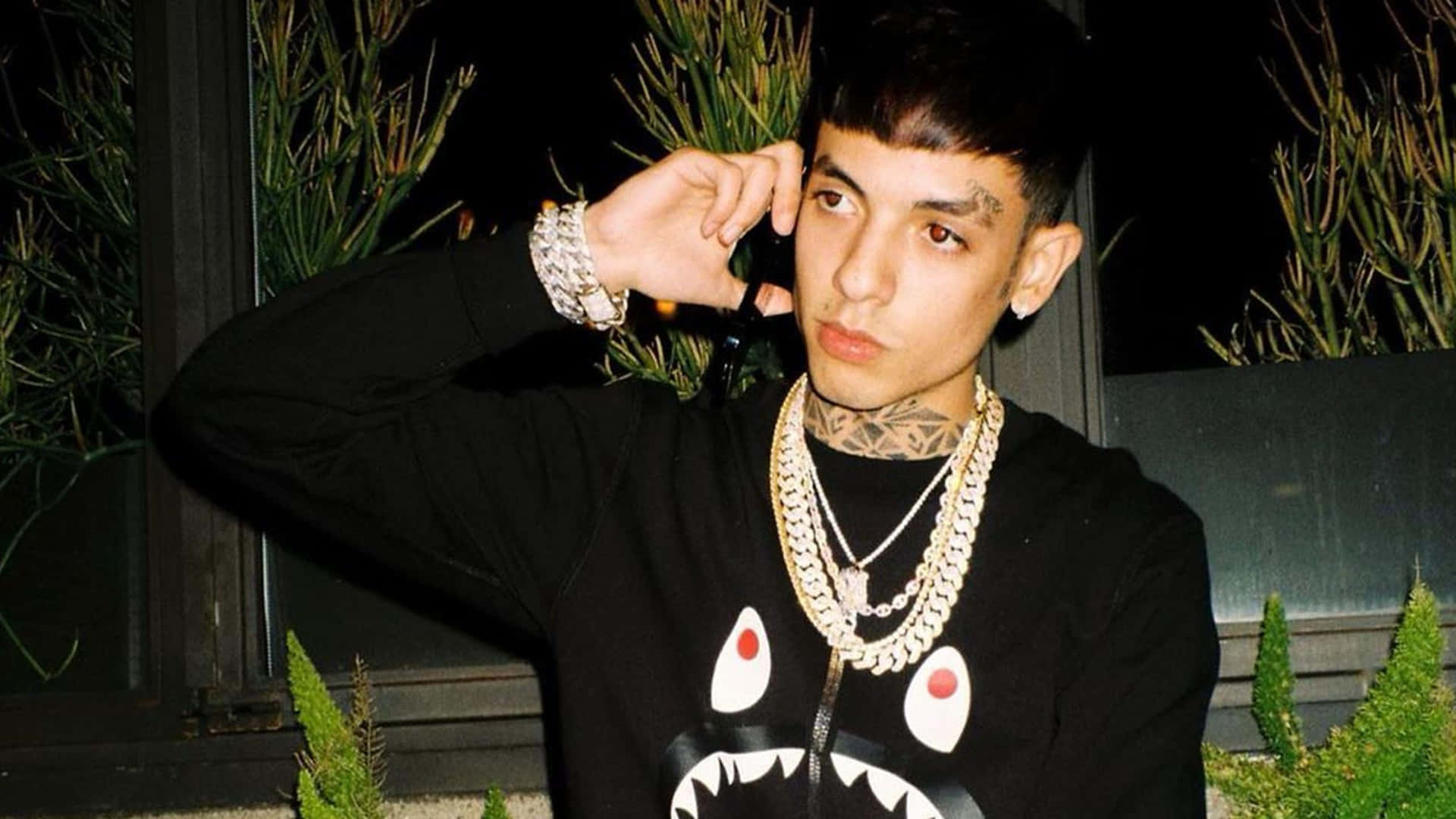 A Man With A Shark Mouth On His Shirt Is Talking On The Phone Background