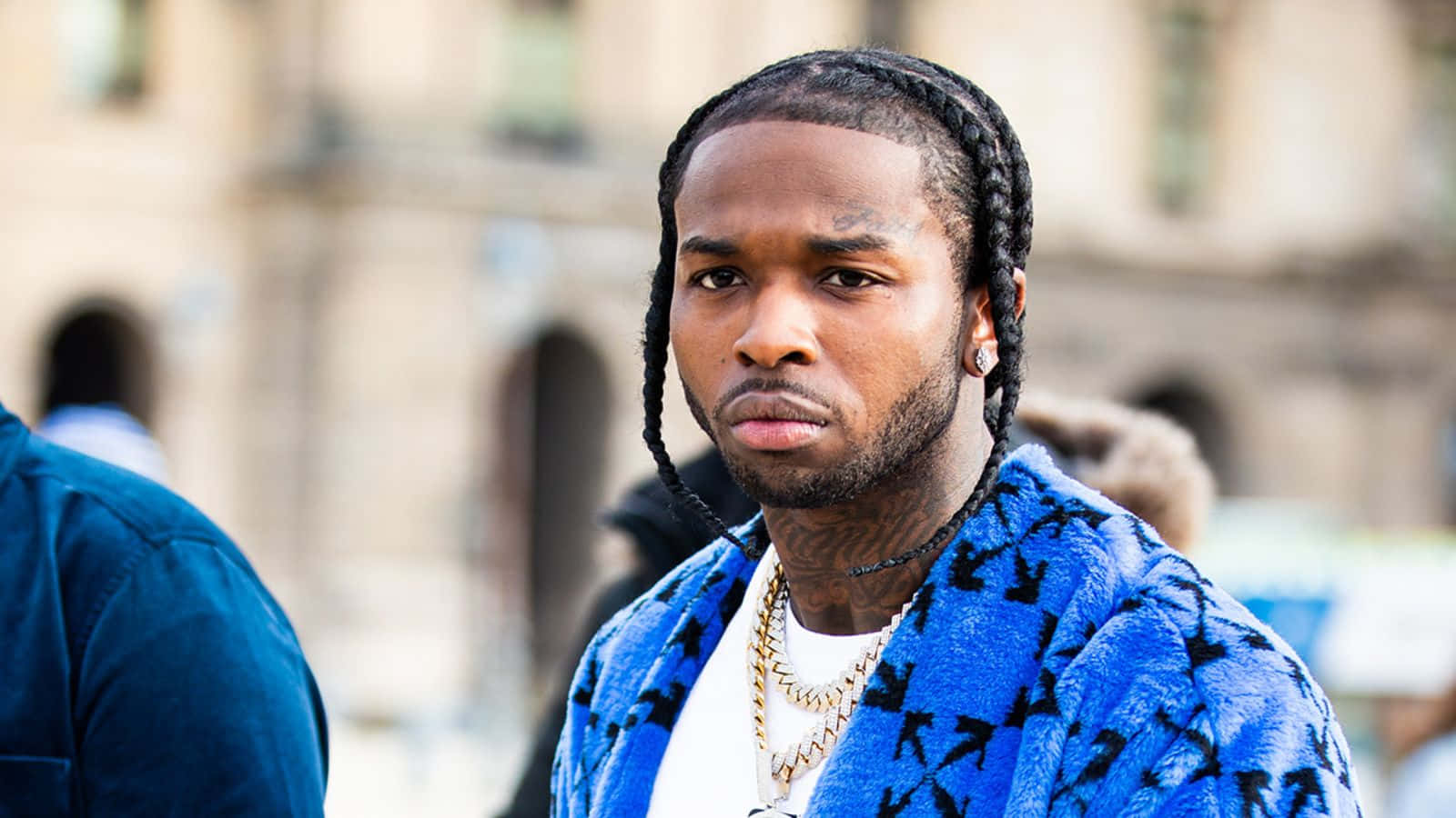 A Man With Dreadlocks And A Blue Jacket Background