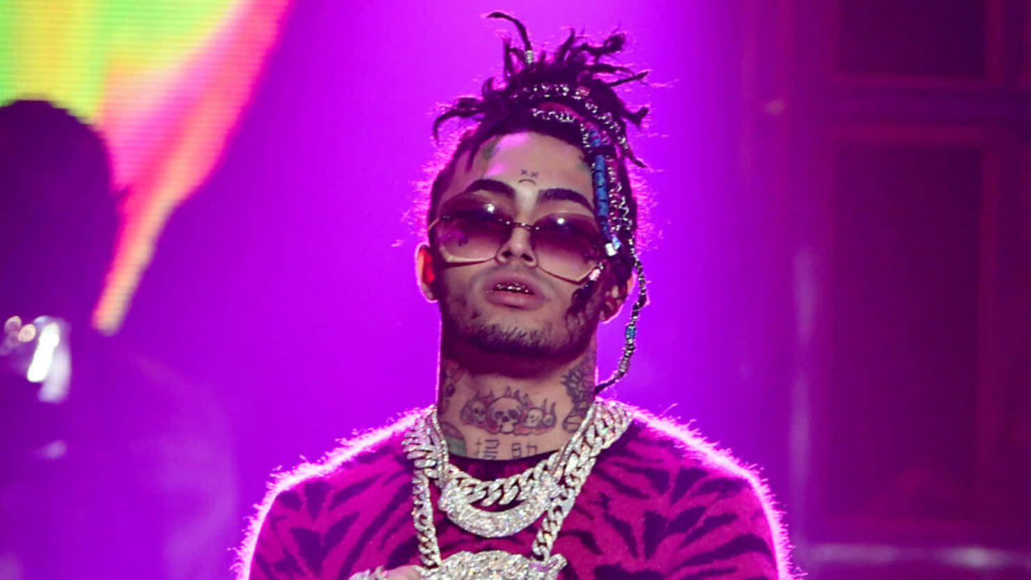 A Man With Dreadlocks And A Necklace On Stage Background