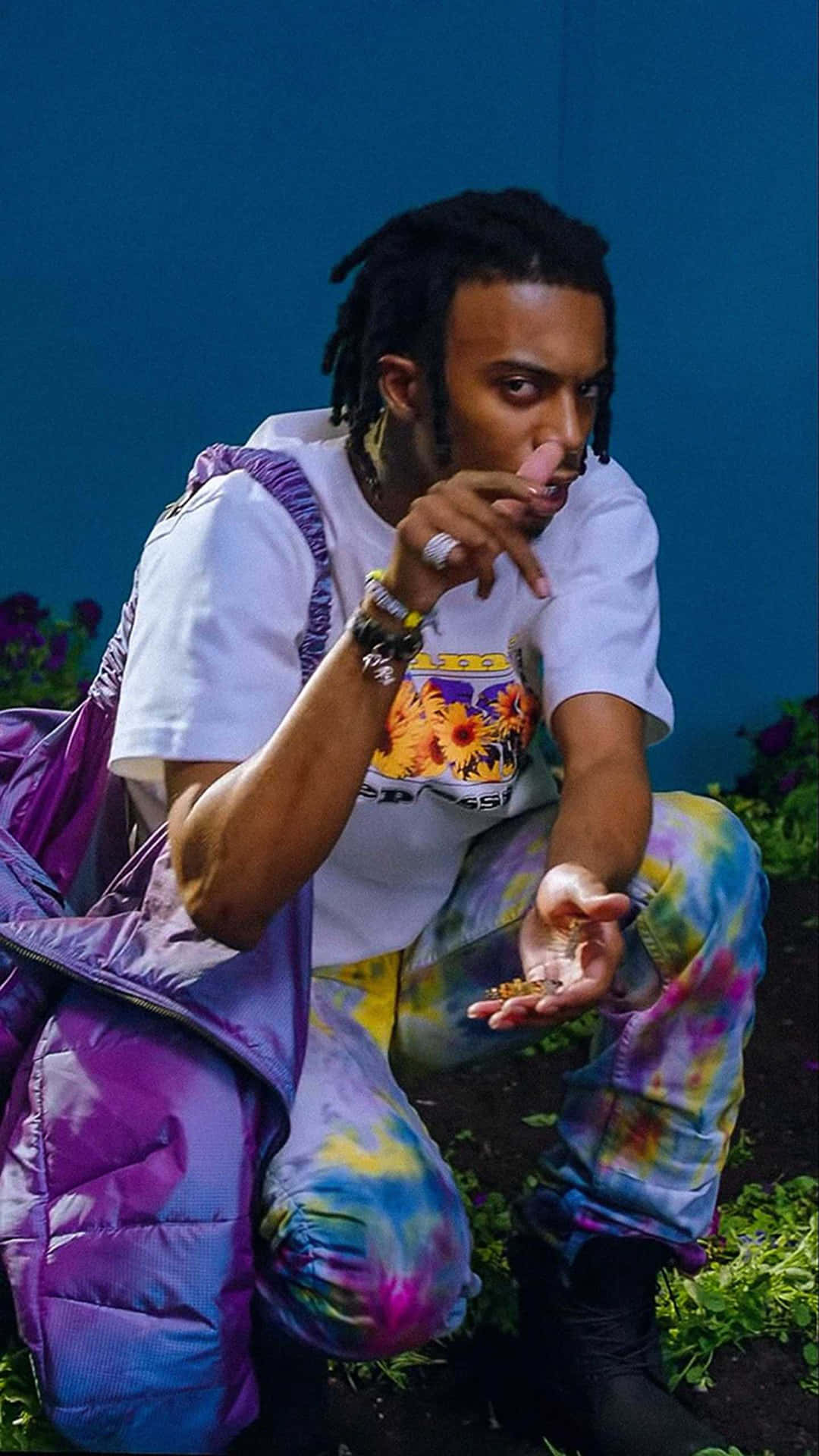 A Man With Dreadlocks And A Purple Backpack Background