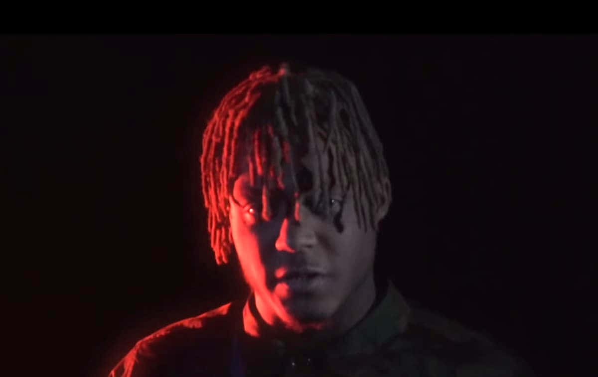 A Man With Dreadlocks In Front Of A Red Light Background