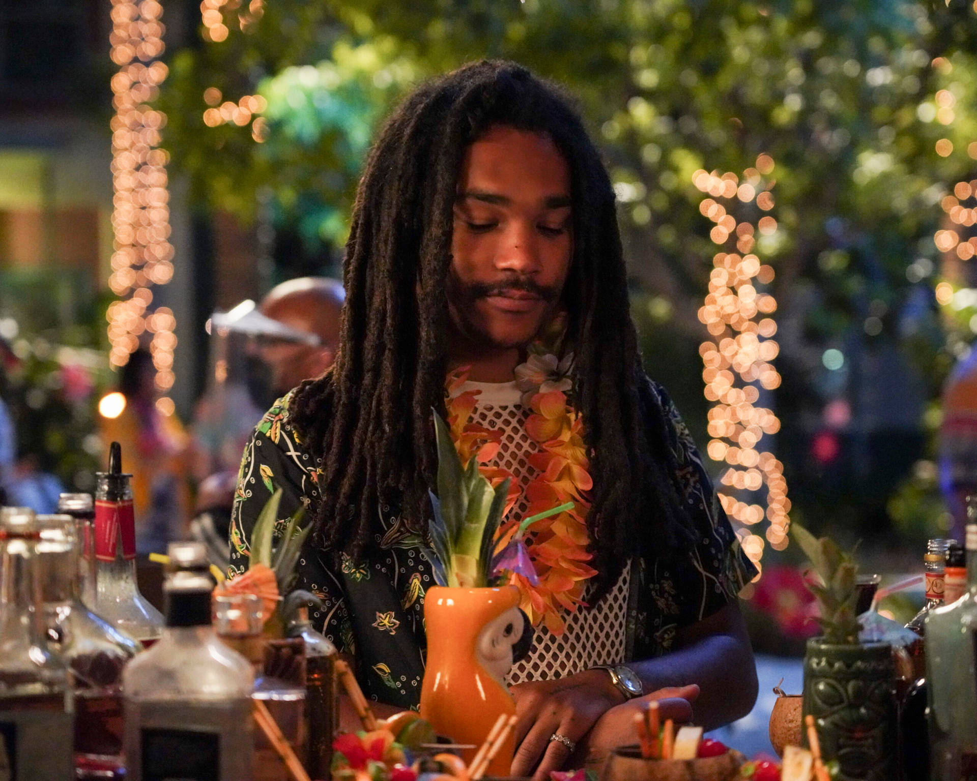 A Man With Dreadlocks Is Making Drinks At A Bar Background