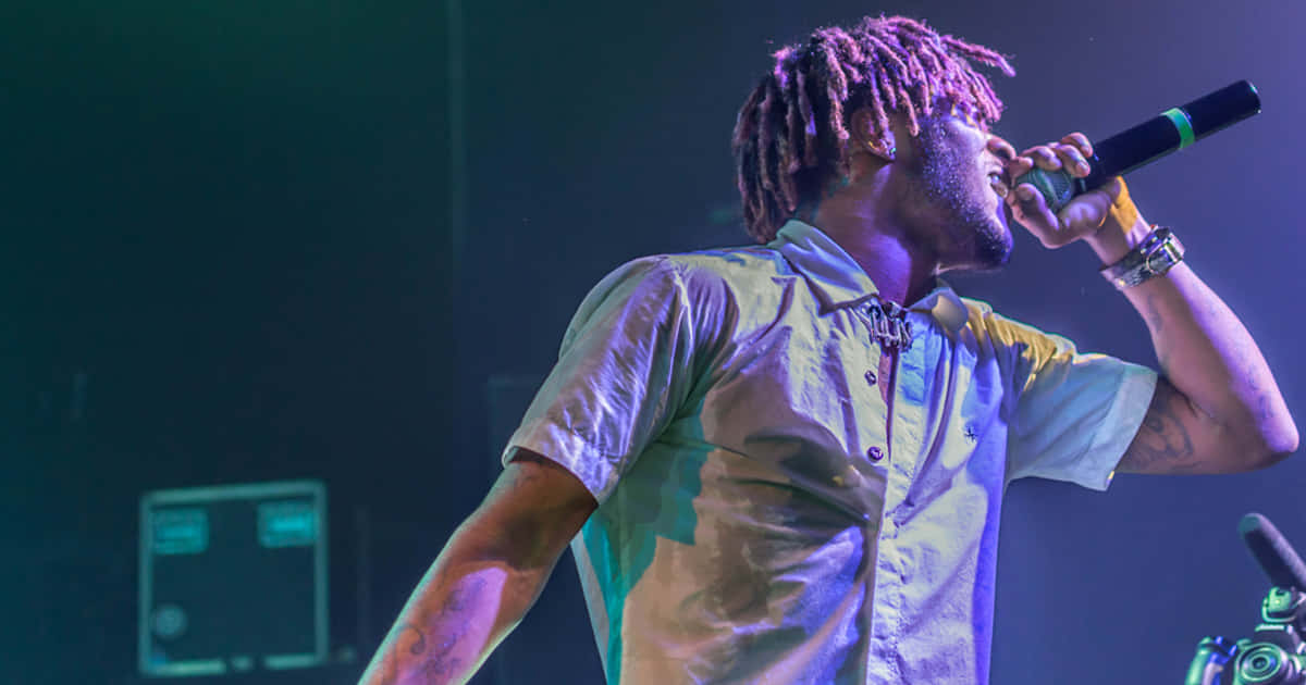 A Man With Dreadlocks Singing Into A Microphone Background