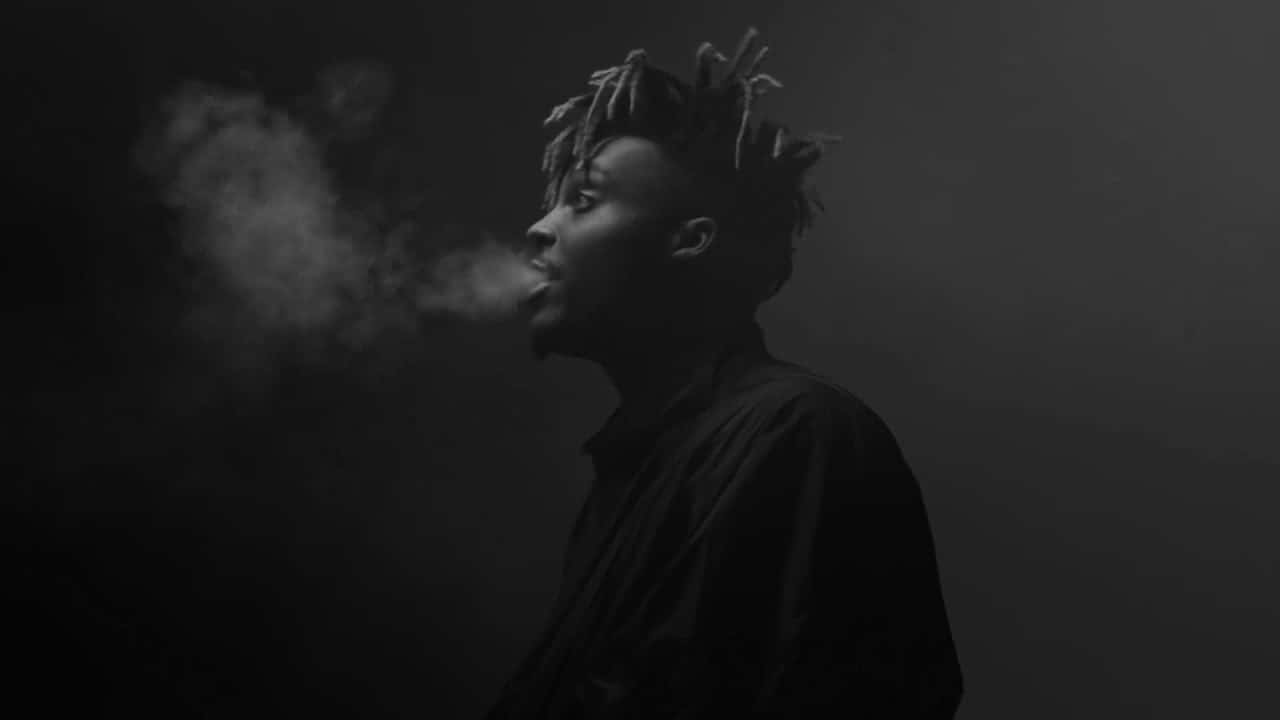 A Man With Dreadlocks Smoking In The Dark Background