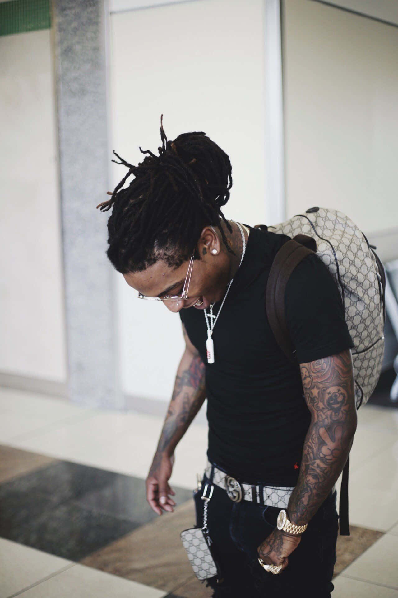 A Man With Dreadlocks Walking Through An Airport Background