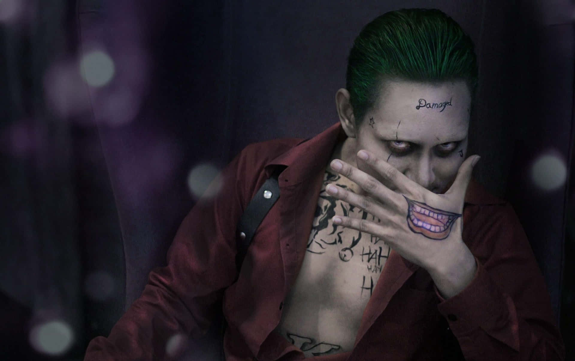 A Man With Green Hair And Tattoos Is Sitting On A Chair Background