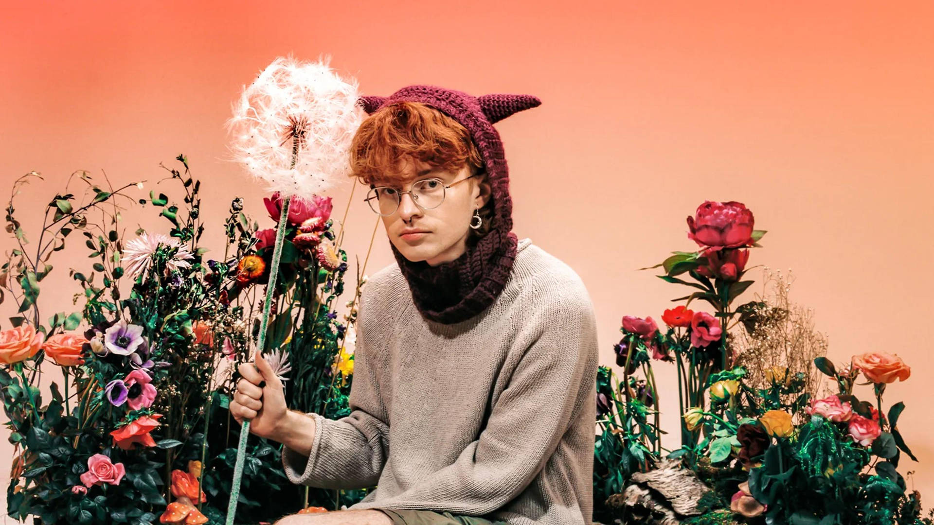 A Man With Red Hair Sitting On A Flower Bed Background