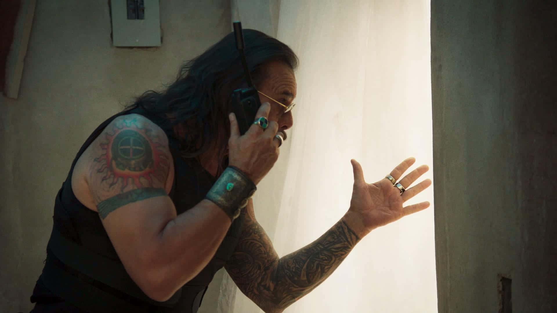 A Man With Tattoos And A Cell Phone In A Room Background