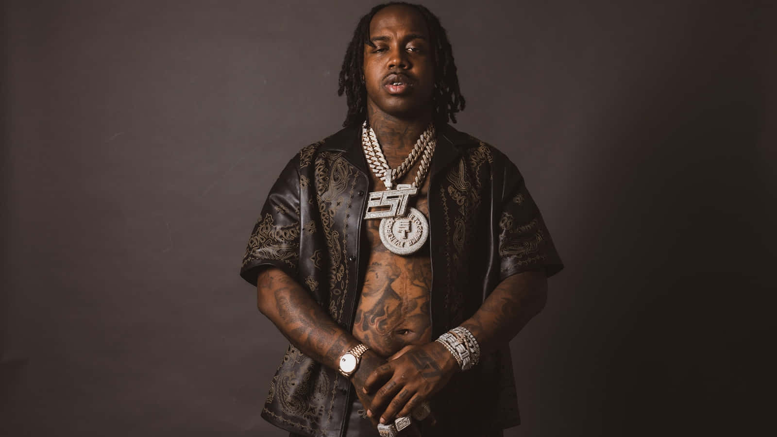 A Man With Tattoos And Chains Posing For A Photo Background