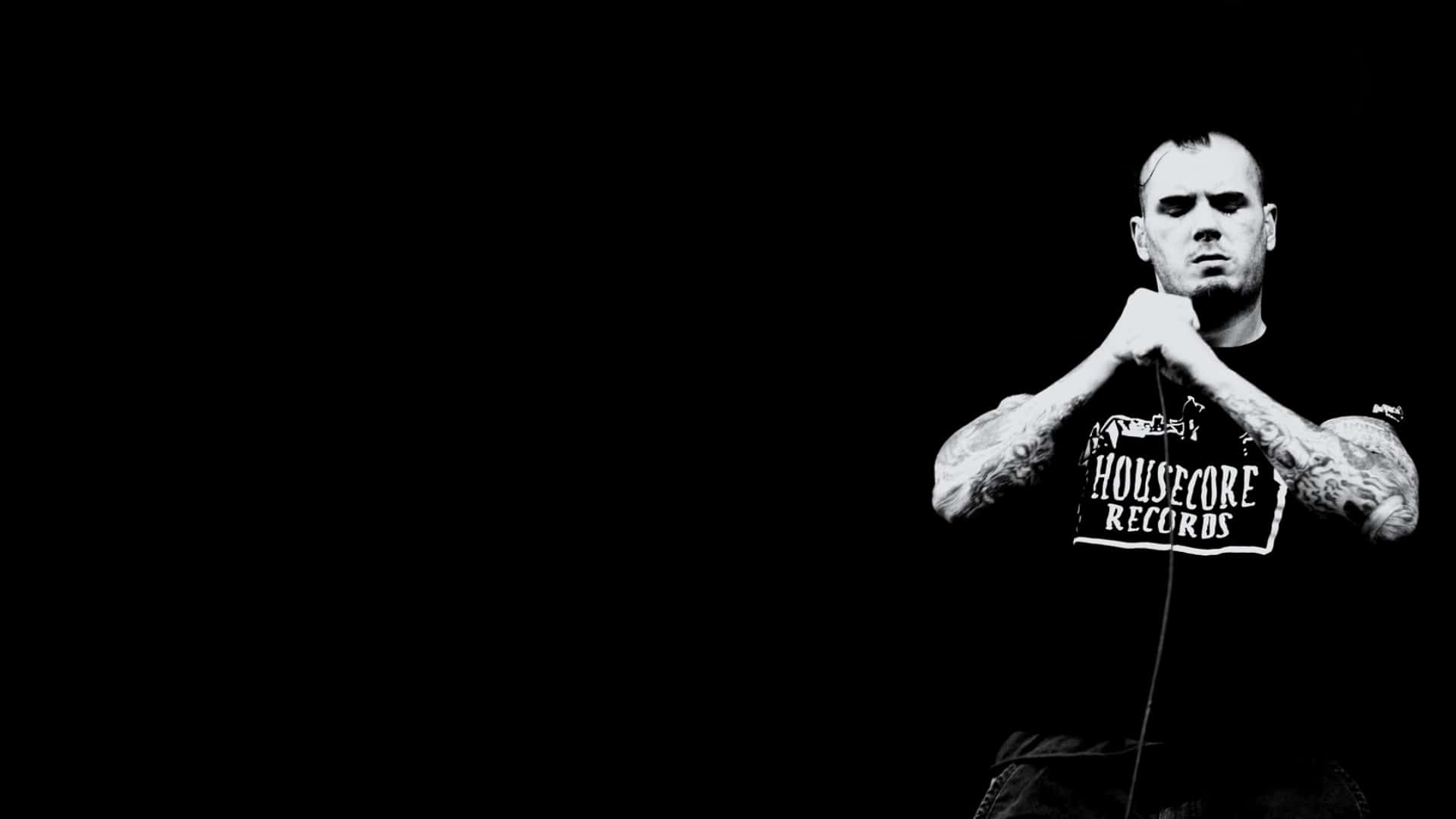 A Man With Tattoos Holding A Microphone Background