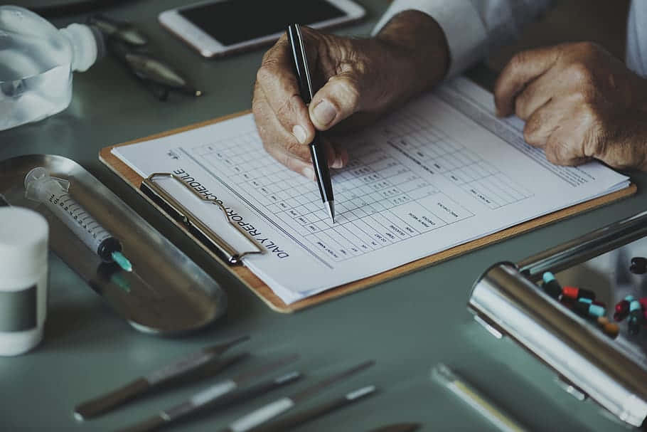 A Man Writing On A Clipboard With Medical Supplies Background