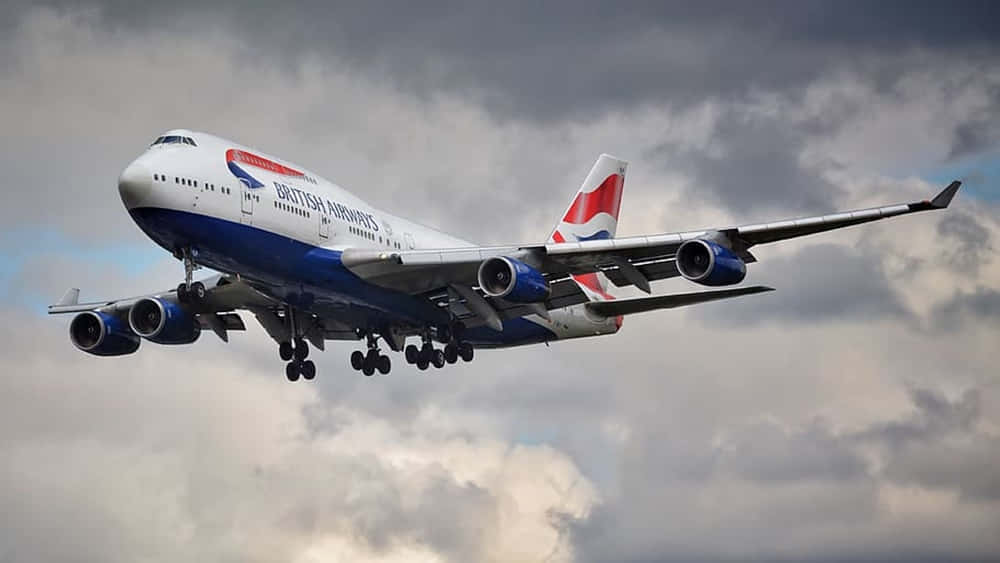 A Massive Jumbo Jet Hovering Above The Clouds Background