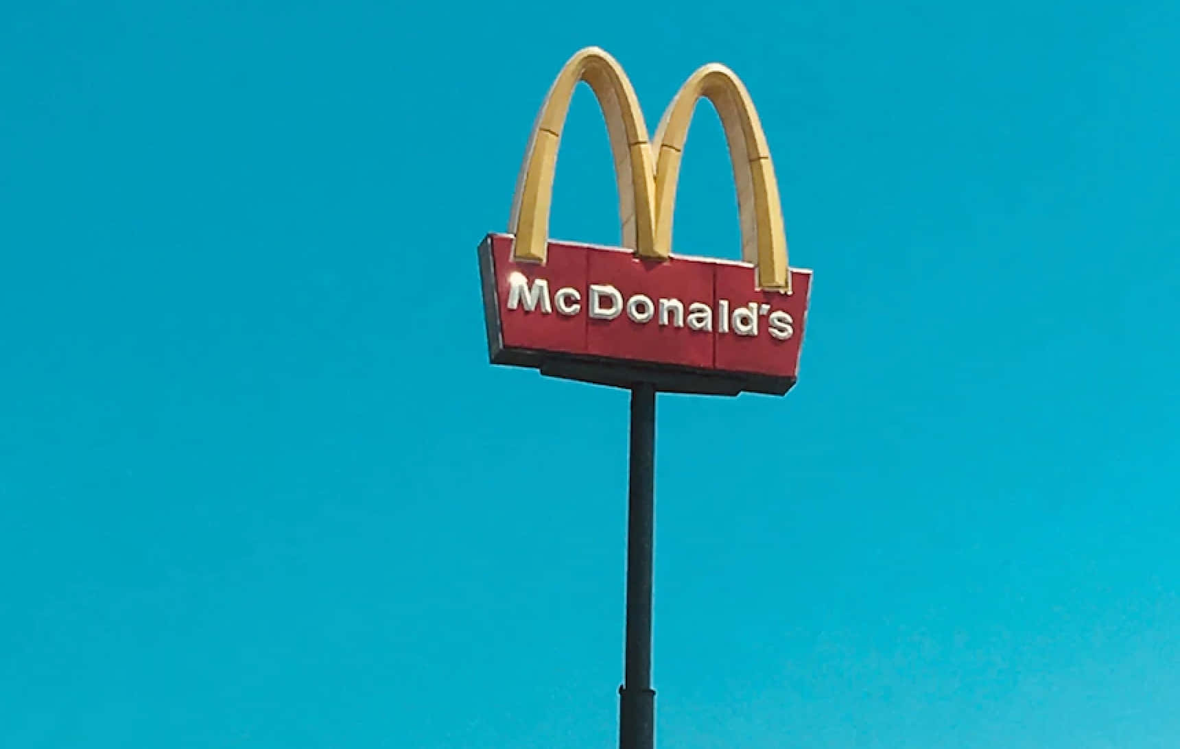 A Mcdonalds Sign With A Blue Sky Background