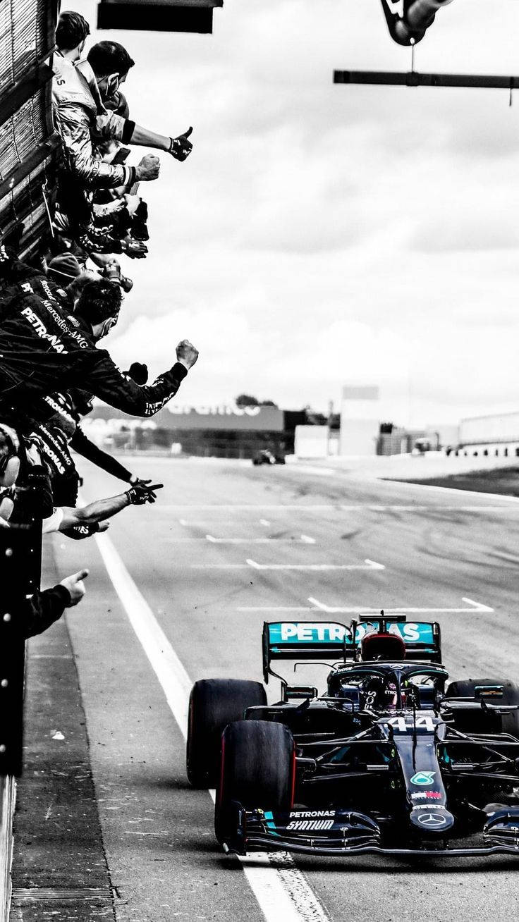 A Mercedes F1 Car Is Being Driven By Fans Background