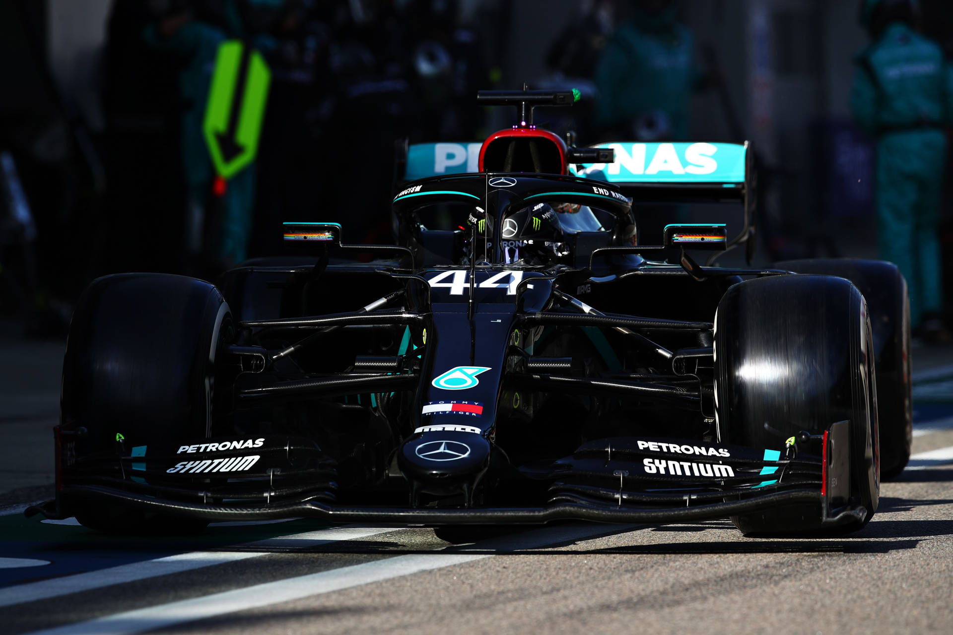 A Mercedes F1 Car Is Driving Down The Track Background