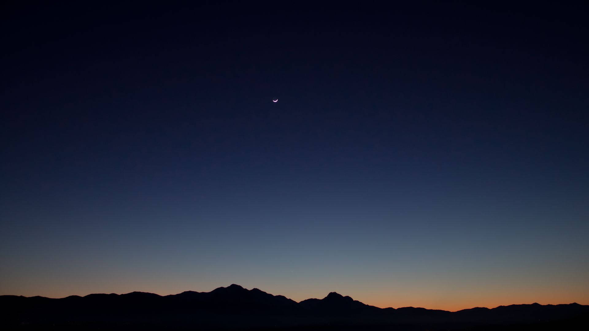 A Moon And A Crescent Are Seen Over The Mountains Background