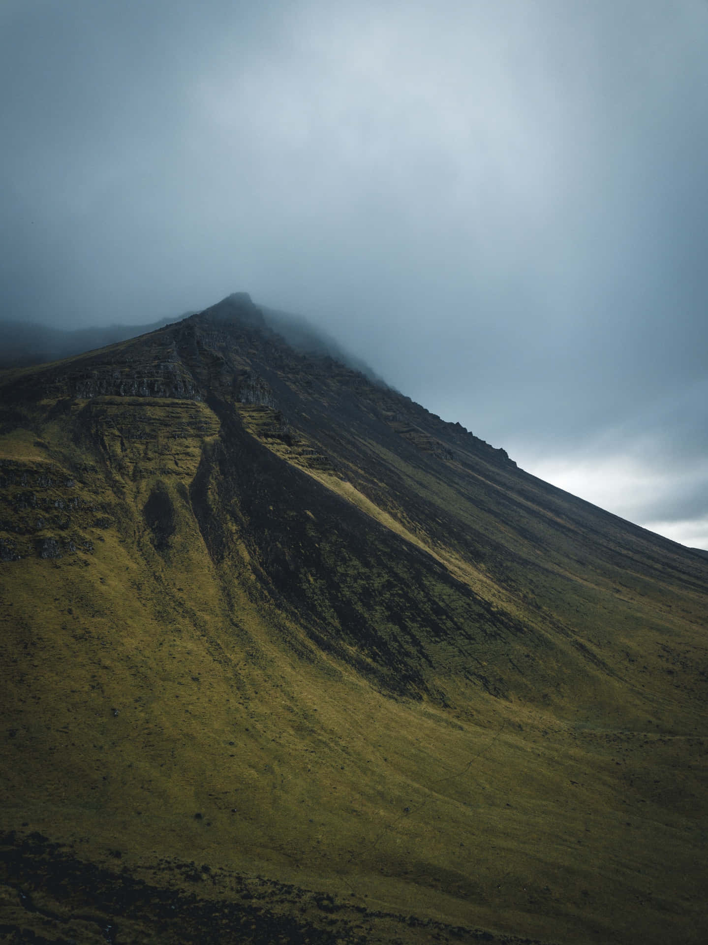 A Mountain Covered In Clouds With Grass And Grass Background