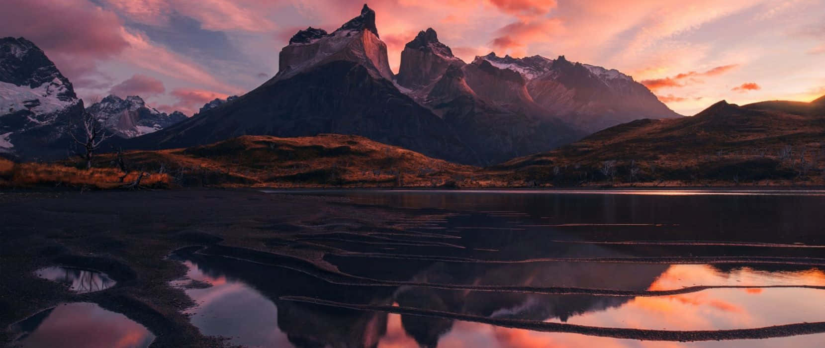 A Mountain Range Is Reflected In A Lake At Sunset Background