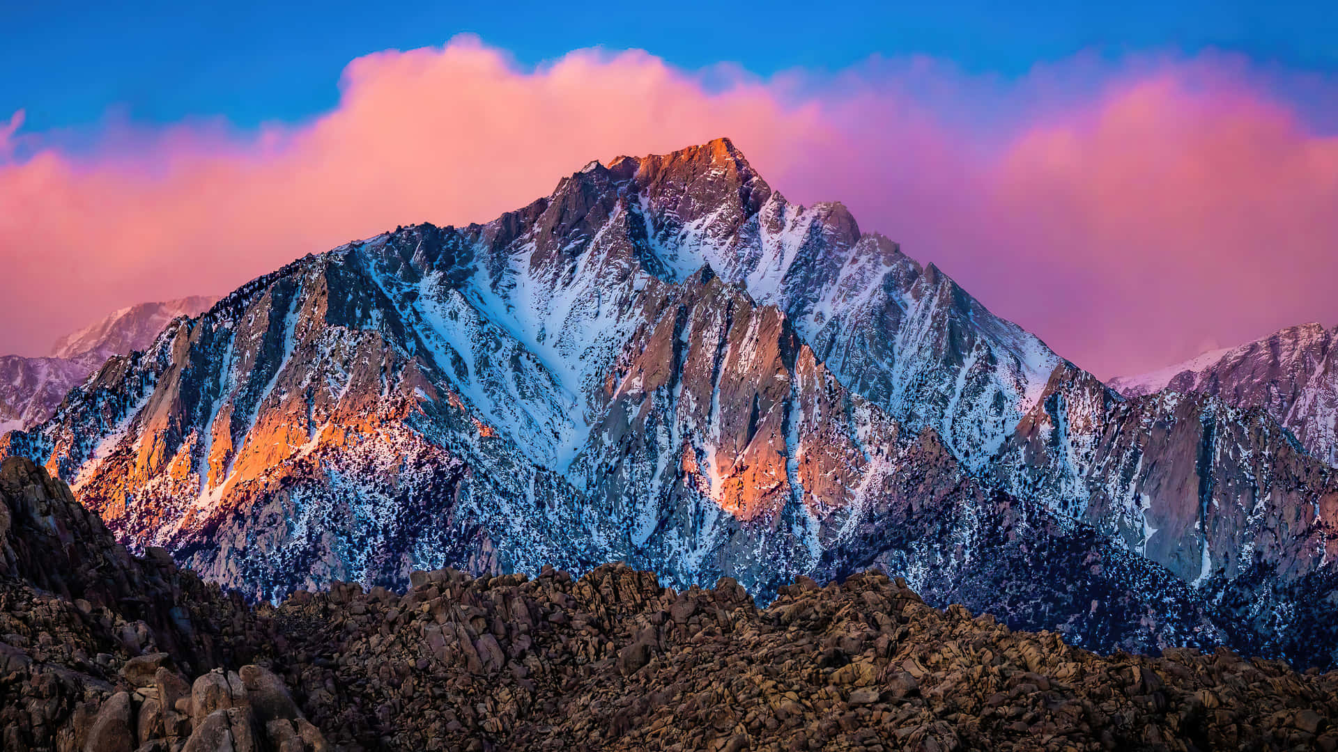 A Mountain Range With A Pink Sky And Snow Background