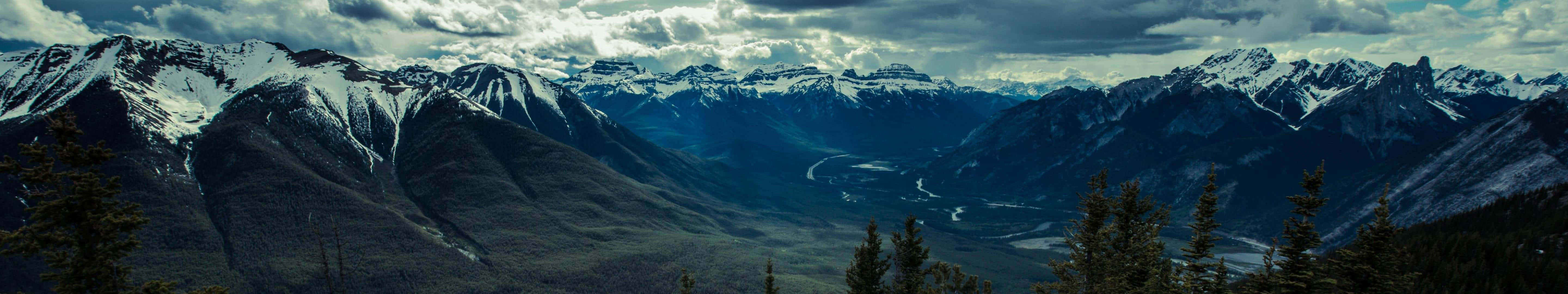 A Mountain Range With Clouds And Snow