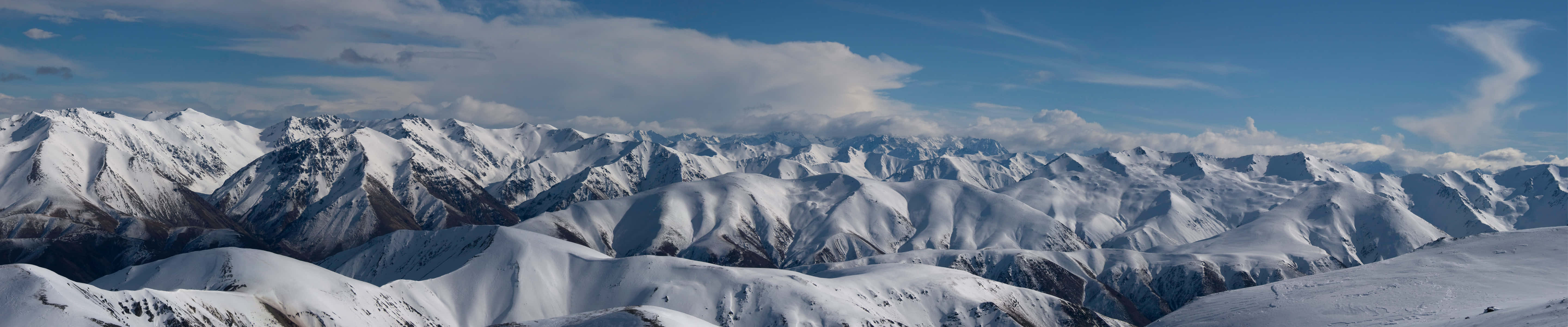 A Mountain Range With Snow Covered Mountains And Clouds