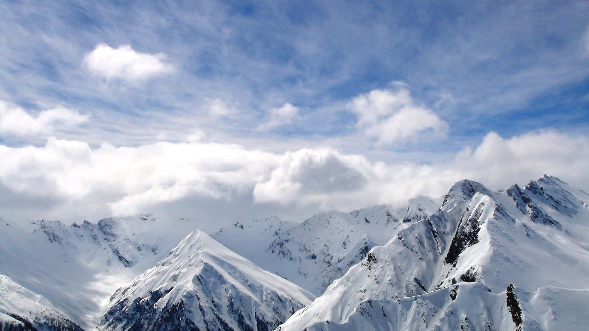 A Mountain Range With Snow Covered Mountains And Clouds Background