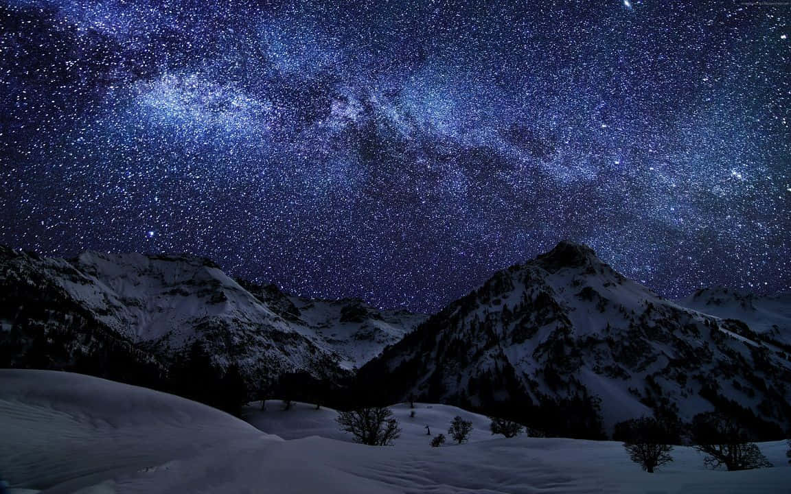 A Mountain Range With Snow Covered Mountains And Stars Above