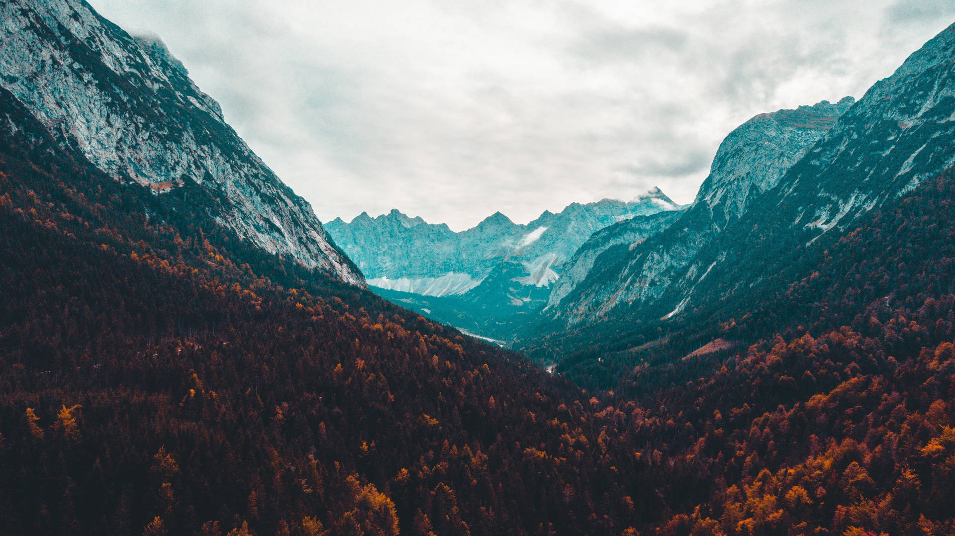 A Mountain Valley With Trees And Clouds