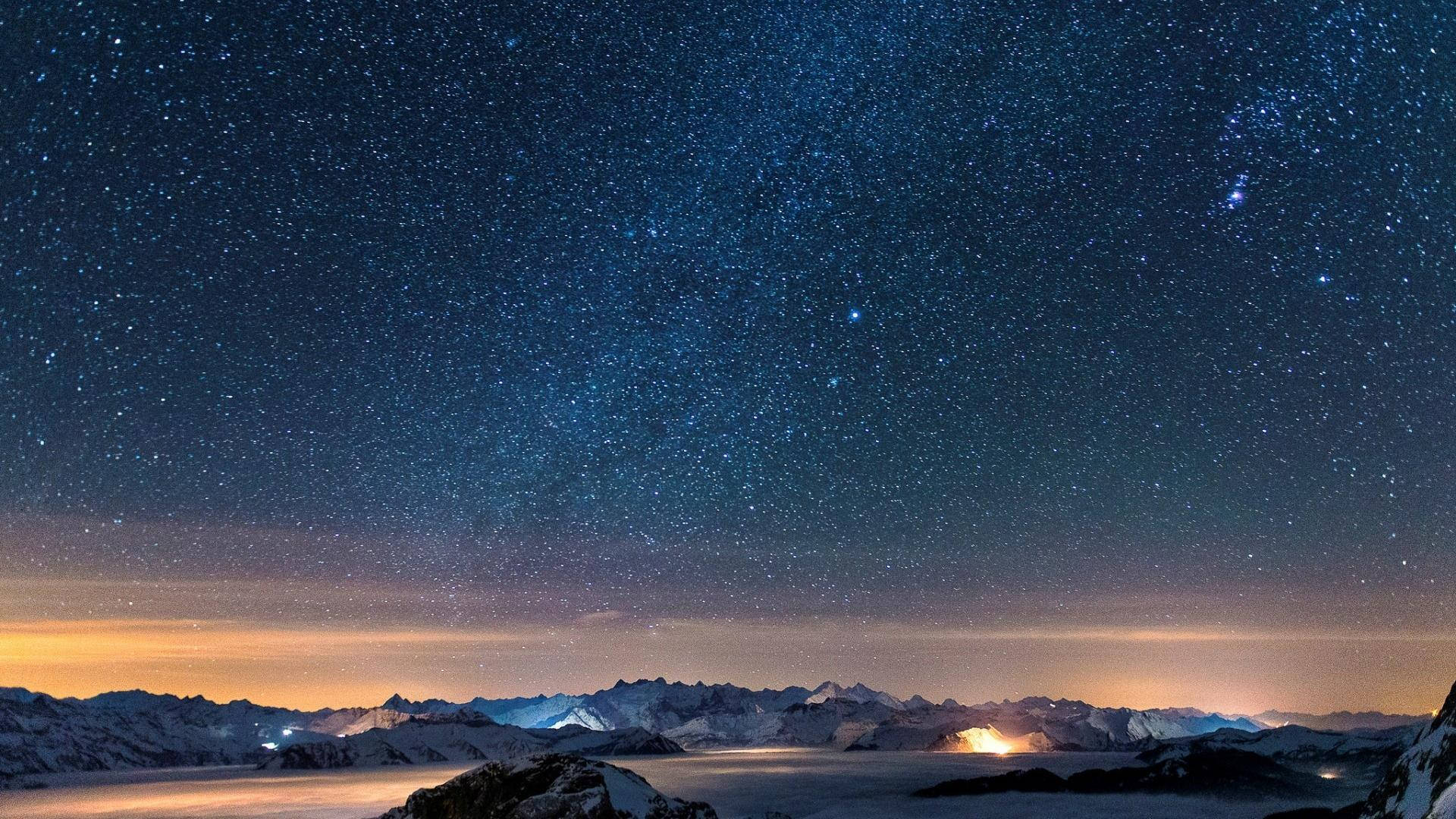 A Mountain With Snow And Stars Above It Background