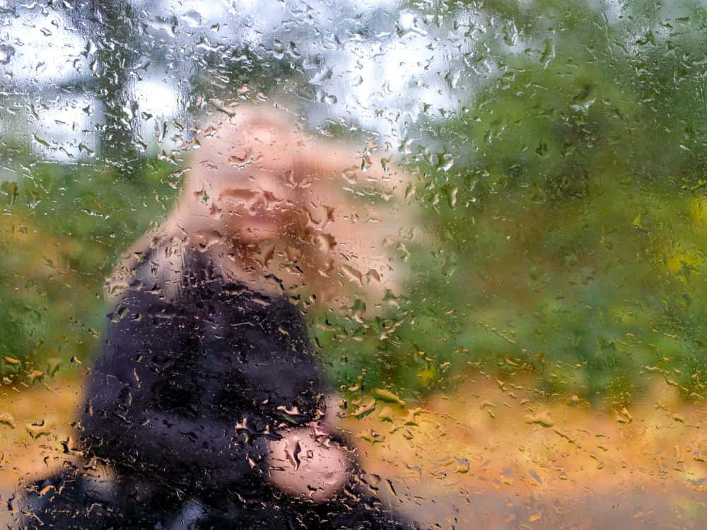 A Mysterious Figure Behind A Wet Glass Background