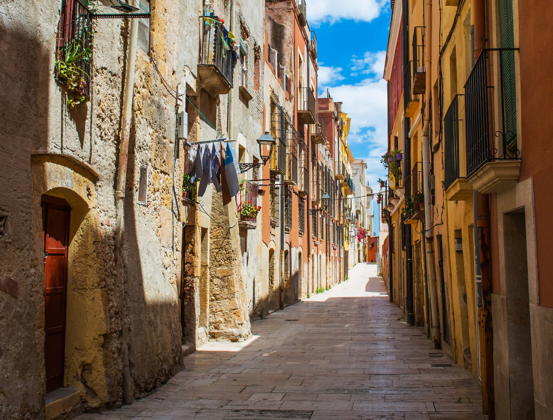 A Narrow Street With Buildings And A Laundry Line Background
