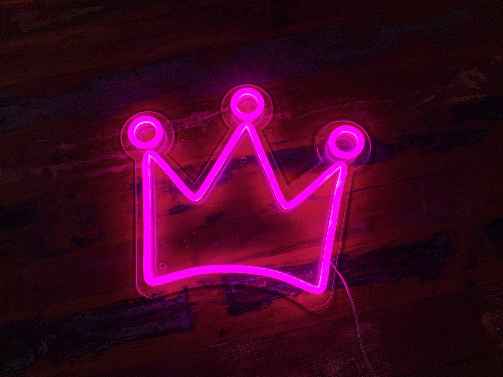 A Neon Crown Sign On A Wooden Floor