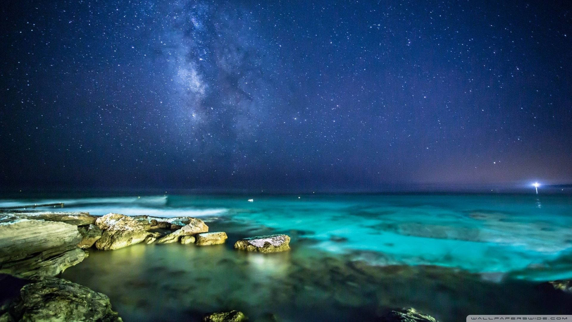 A Night Sky With Stars And A Milky Over A Rocky Beach Background