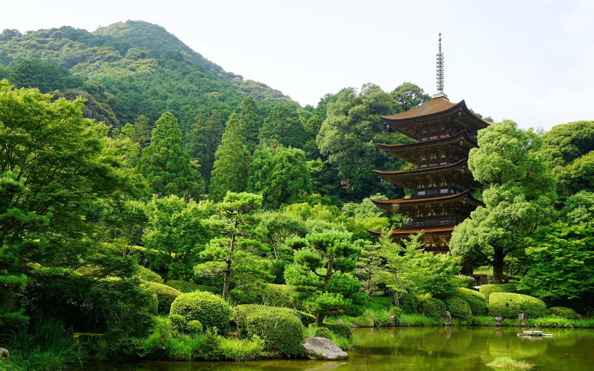 A Pagoda Tower In A Garden With Trees And Bushes