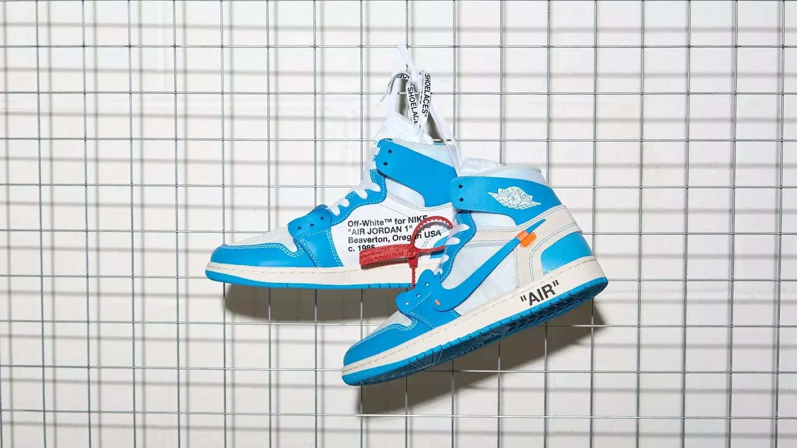 A Pair Of Air Jordan 1 High Sneakers Hanging On A Wire Background