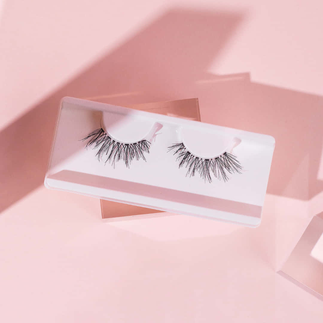 A Pair Of False Lashes On A Pink Background Background