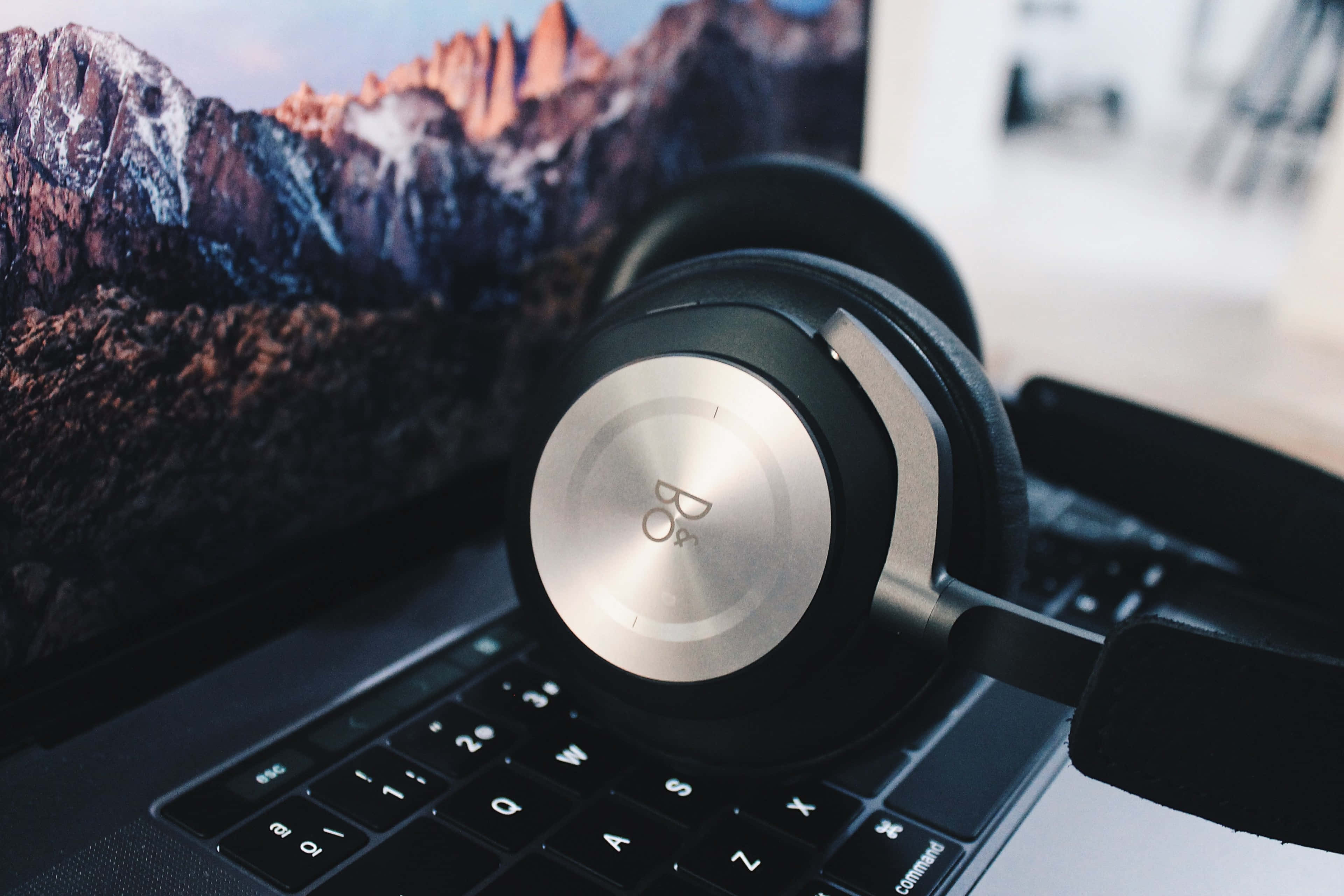 A Pair Of Headphones Beside A Laptop Background