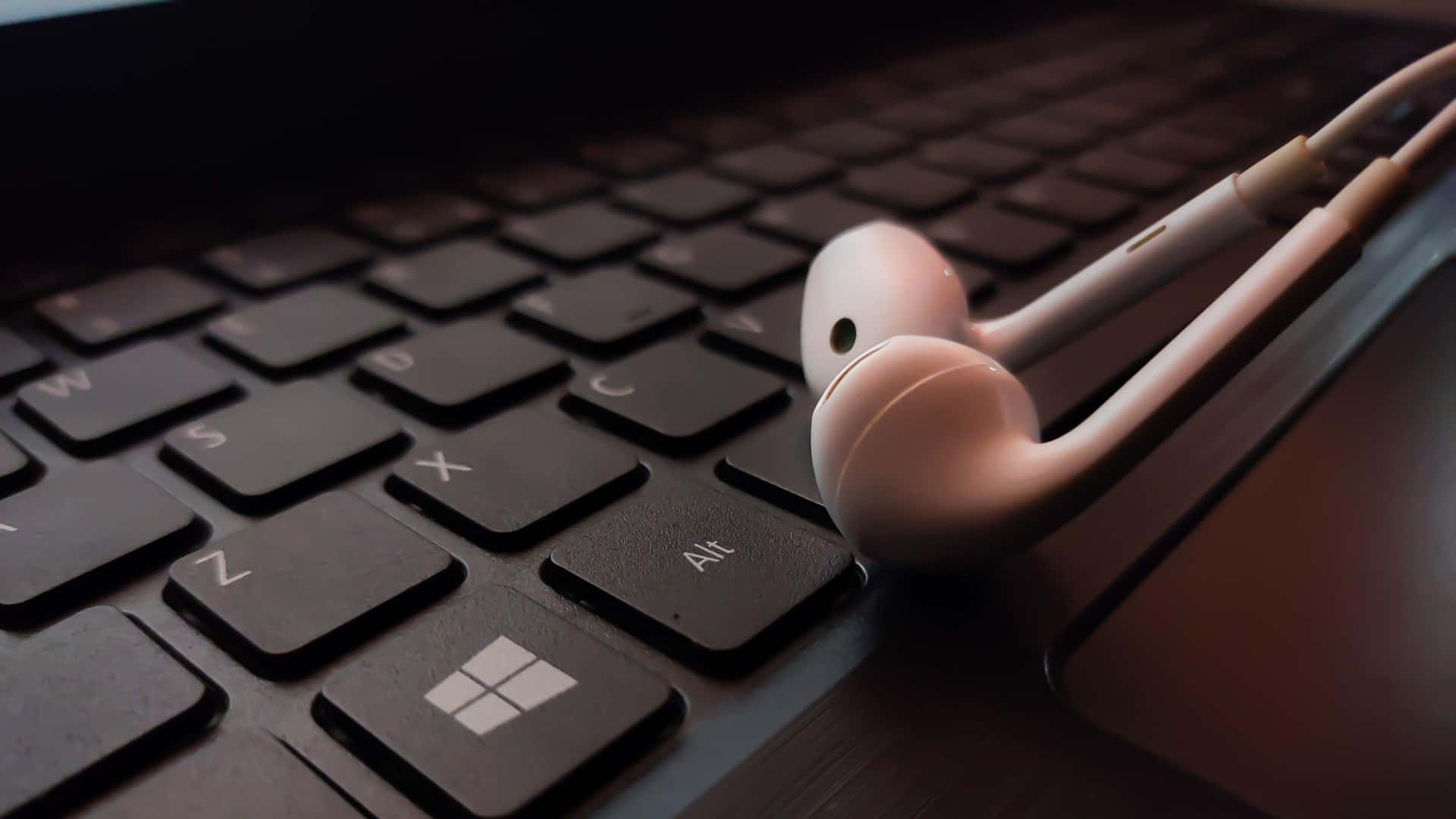 A Pair Of Headphones On A Laptop Keyboard Background