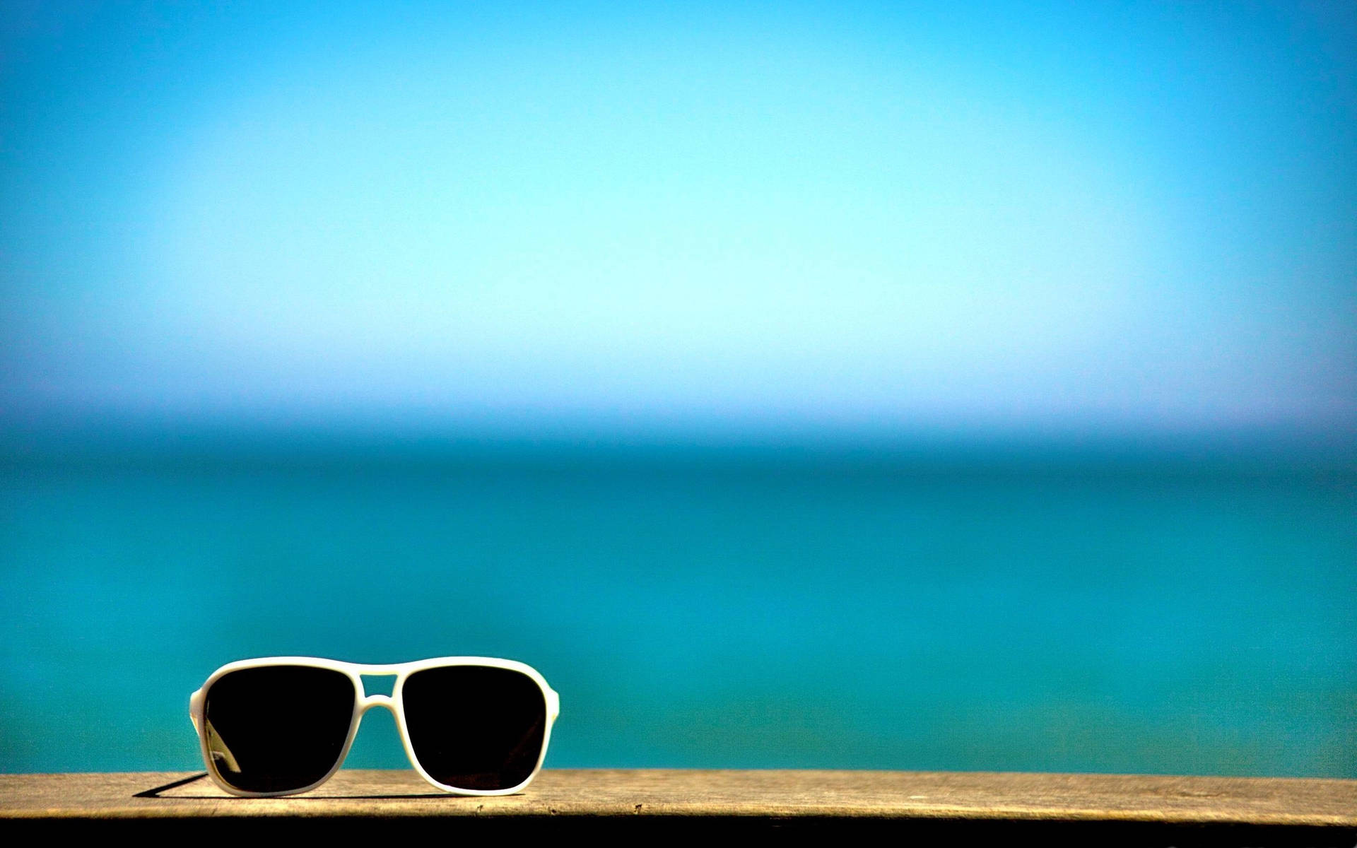 A Pair Of Sunglasses On A Wooden Bench Background