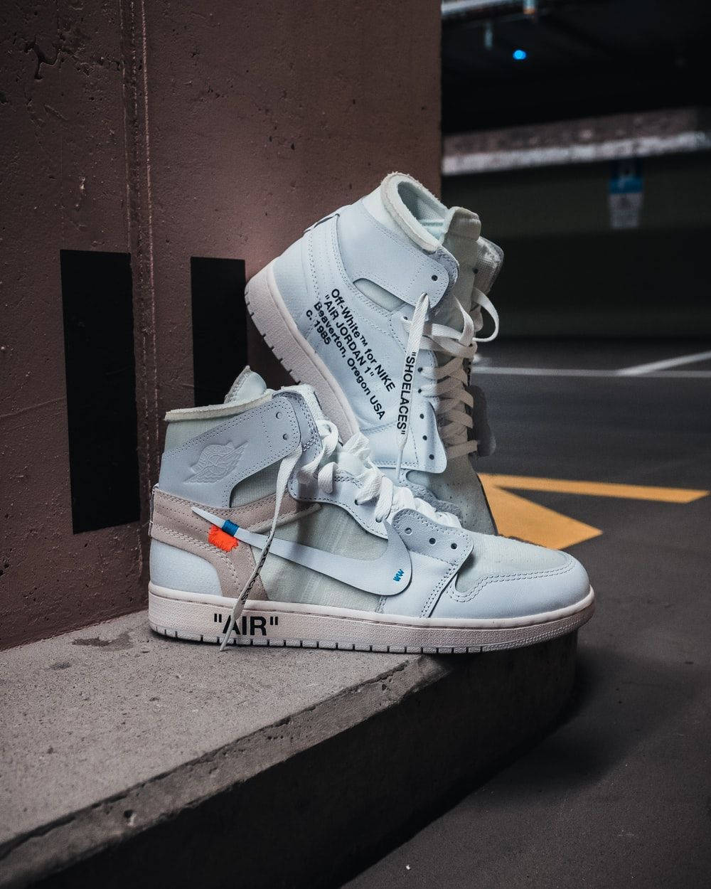 A Pair Of White Air Jordan 1 High Sneakers Sitting On A Concrete Wall