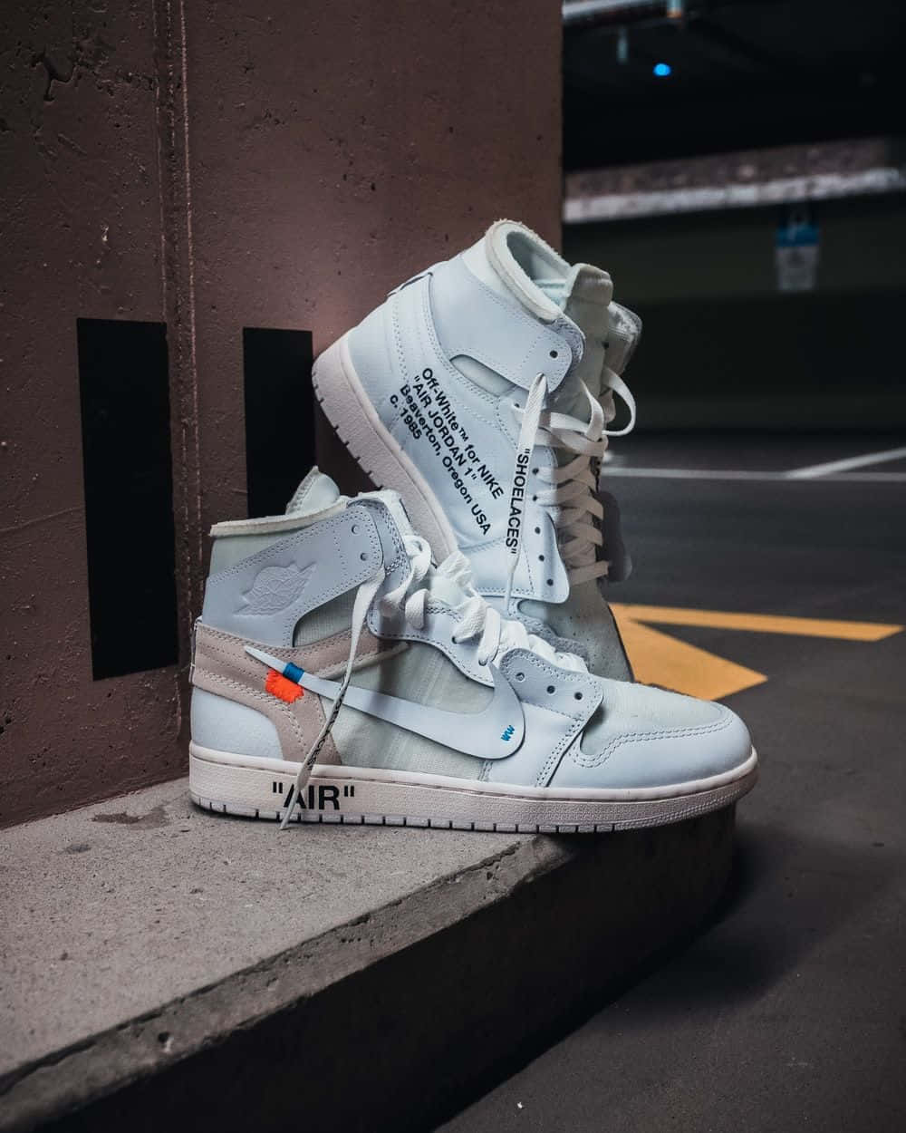 A Pair Of White Air Jordan 1 High Sneakers Sitting On A Concrete Wall Background
