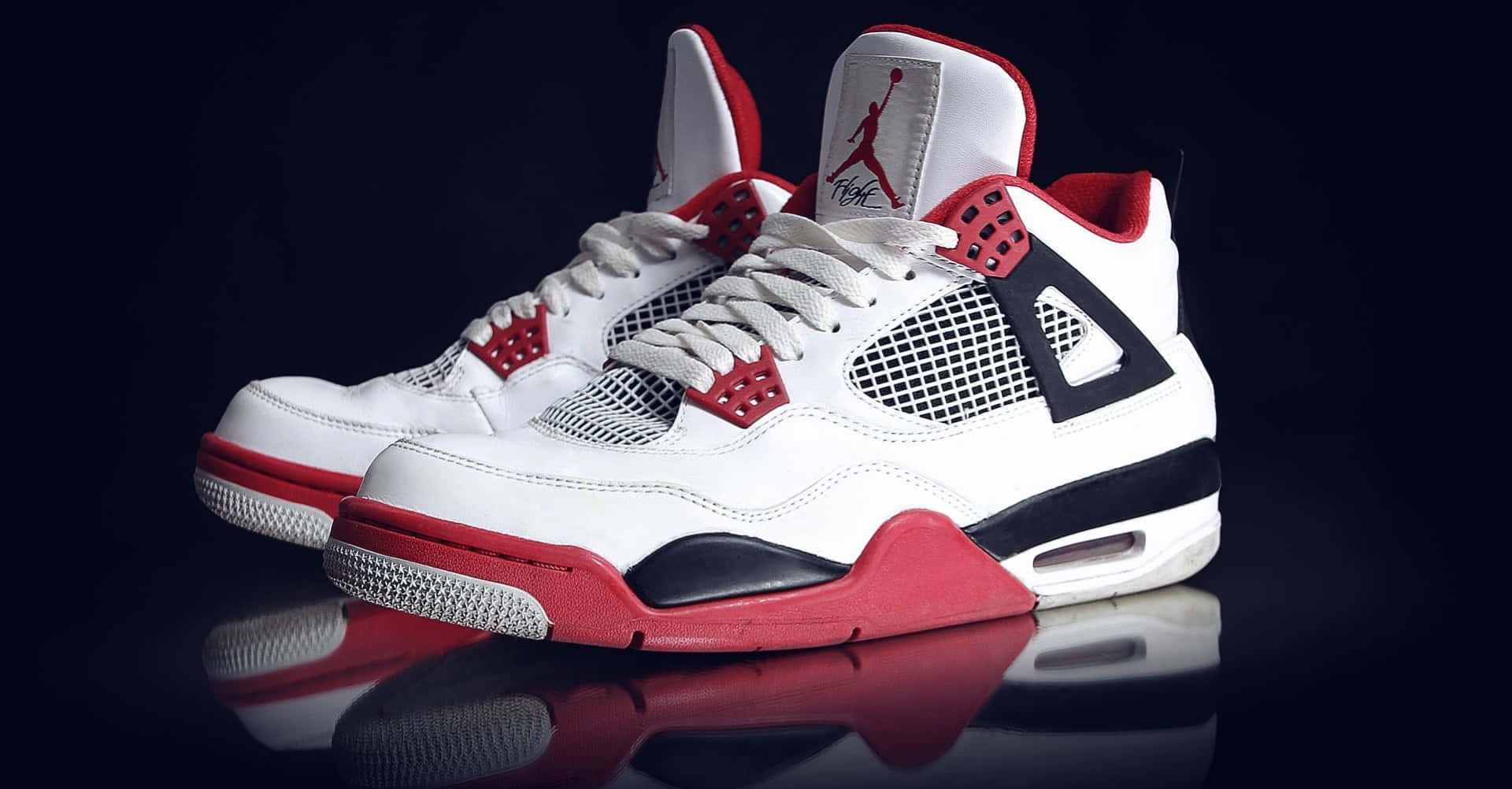 A Pair Of White And Red Air Jordan 4 Sneakers