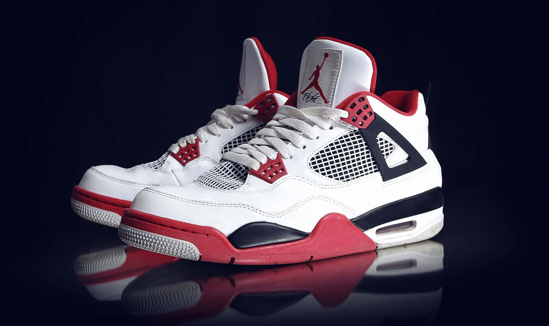A Pair Of White And Red Air Jordan 4 Sneakers Background