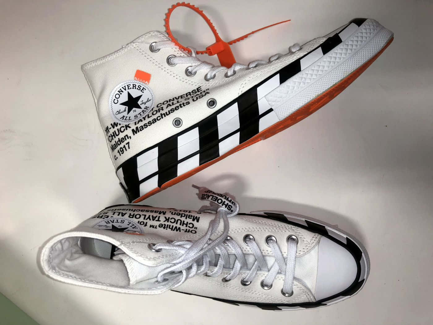 A Pair Of White Converse Sneakers With Orange And Black Stripes Background